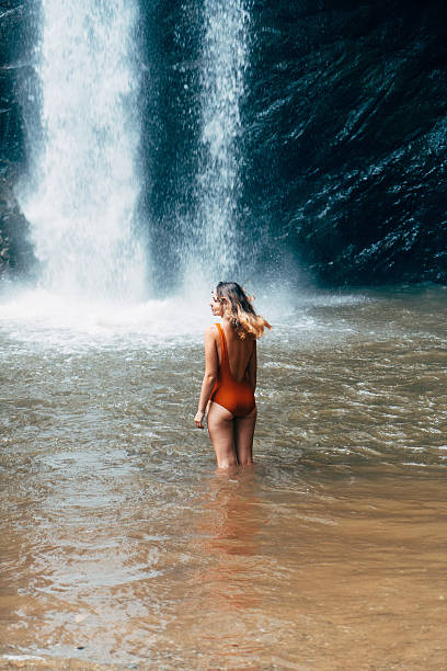 istock Woman swimming in tropical waterfall 627815064
