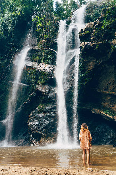 istock Woman standing near the  tropical waterfall 627815230