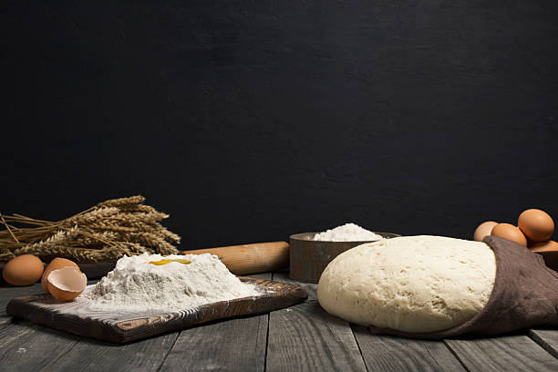 istock Fresh dough with flour and eggs on wooden table 627852320
