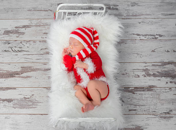 istock cute sleeping baby in red hat on little bed 627853448