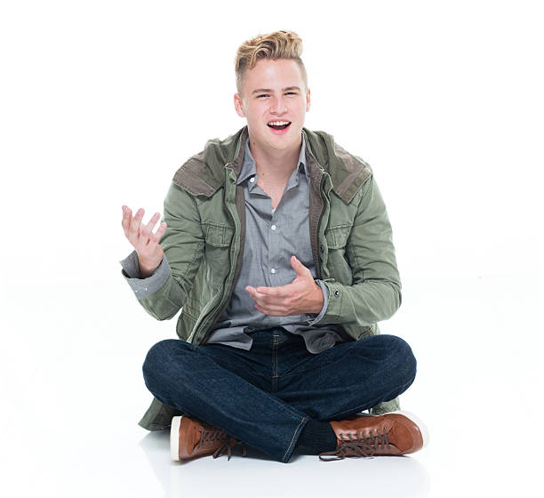istock Smiling man sitting on floor and presenting 627855328