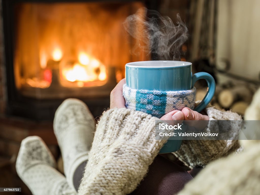 Warming and relaxing near fireplace. Warming and relaxing near fireplace with a cup of hot drink. Heat - Temperature Stock Photo