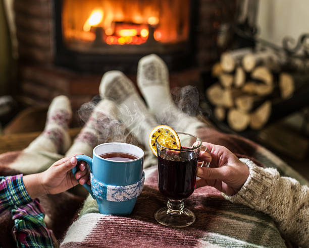 Warming and relaxing near fireplace. Warming and relaxing near fireplace. Woman feet near the cup of hot drink in front of fire. heat home interior comfortable human foot stock pictures, royalty-free photos & images