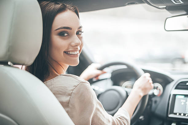 Confident and beautiful. Rear view of attractive young woman in casual wear looking over her shoulder while driving a car contains people stock pictures, royalty-free photos & images