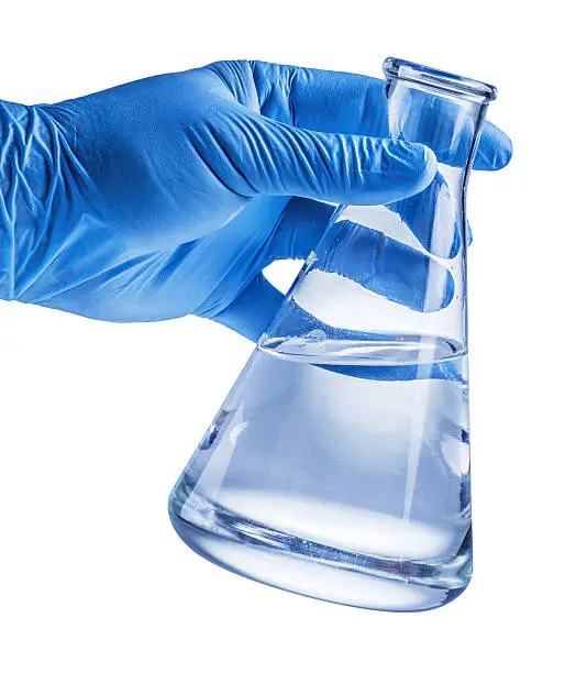 Laboratory beaker in analyst's hand in plastic glove. File contains clipping paths.