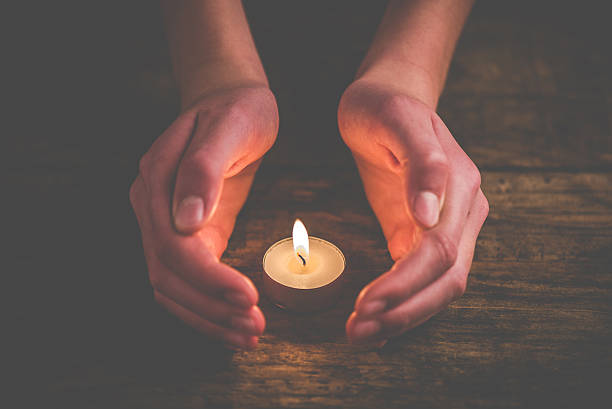 istock hands that protect the flame of a candle 627870242