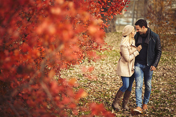 Young embraced couple taking a walk in autumn park. stock photo