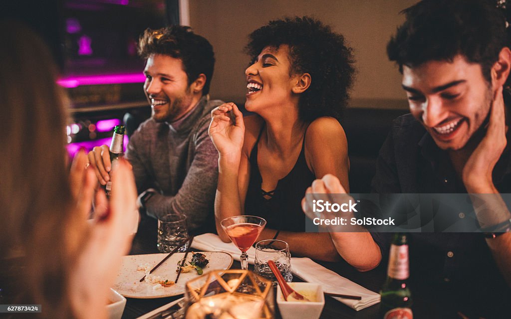 Friends Enjoying a Meal Group of friends enjoying a late evening meal in a restaurant. Friendship Stock Photo