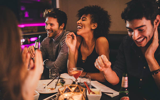 Friends Enjoying a Meal Group of friends enjoying a late evening meal in a restaurant. cocktail party stock pictures, royalty-free photos & images