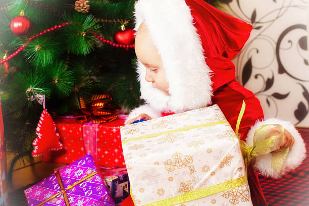 Little boy in a Christmas tree with gifts stock photo