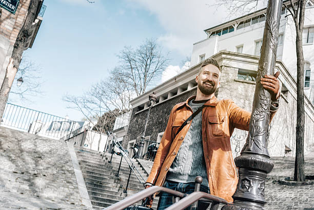 happy bearded man leaning on iron lantern in Monmartre Paris