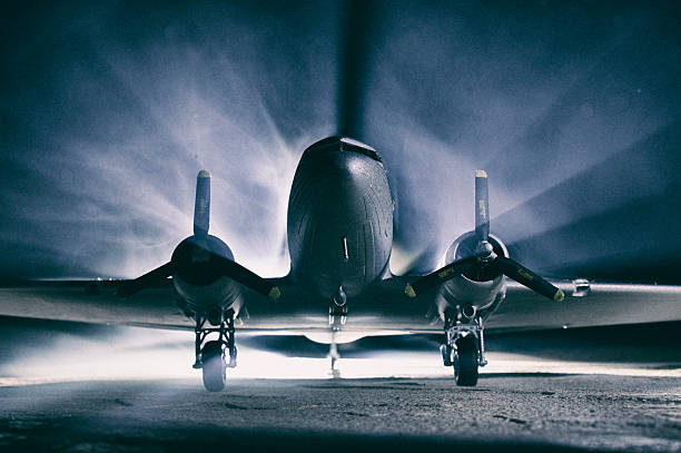 A model DC3 Dakota on a fog-bound runway, with light coming in from the left of the scene. Photographed and processed in classic film noir style.