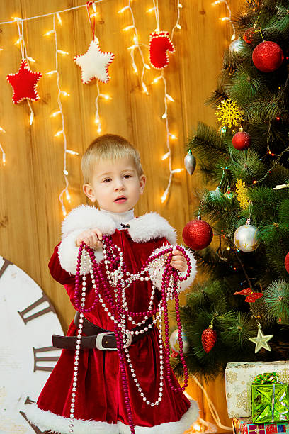Little boy in a Christmas tree with gifts stock photo