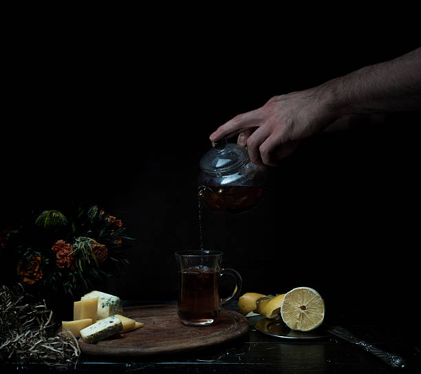 istock still life. male hands pour tea in transparent cup. dark 627892638