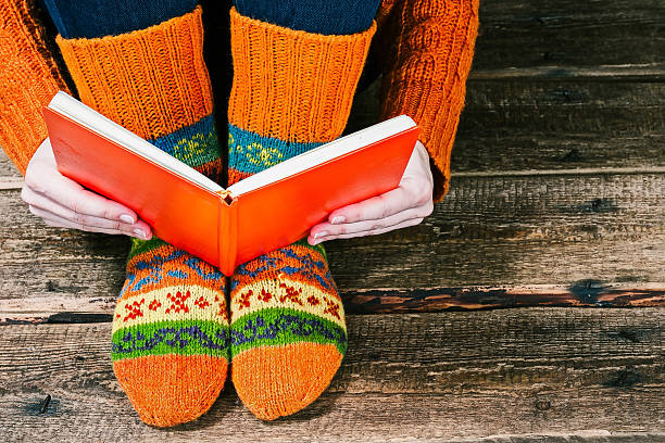 Feet with book Human feet in colorful winter socks on the floor and hands with book. Closeup view clew bay stock pictures, royalty-free photos & images