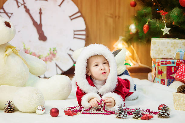 Little boy in a Christmas tree with gifts stock photo