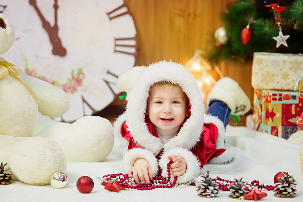Little boy in a Christmas tree with gifts stock photo