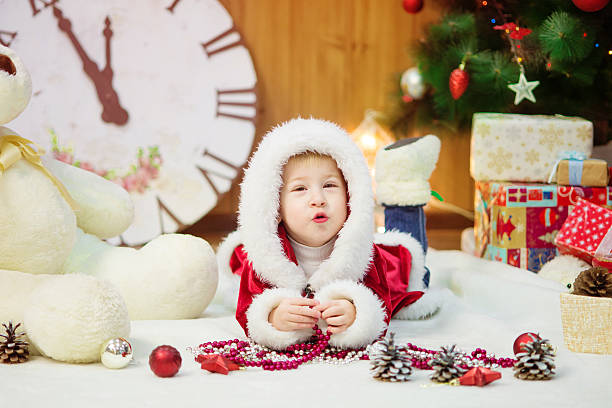 Little boy in a Christmas tree with gifts stock photo