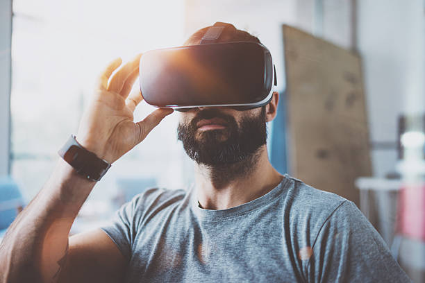 istock Bearded man wearing virtual reality glasses in modern interior design 627904086