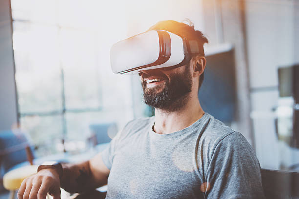 istock Bearded man wearing virtual reality glasses in modern interior design 627904268