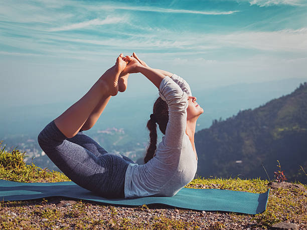 woman doing ashtanga vinyasa yoga asana dhanurasana - bow pose - mountain himalayas india mountain range imagens e fotografias de stock