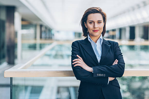 Trust in our business Young woman in business wear standing with armes crossed in business environment, with copy space. financial occupation photos stock pictures, royalty-free photos & images