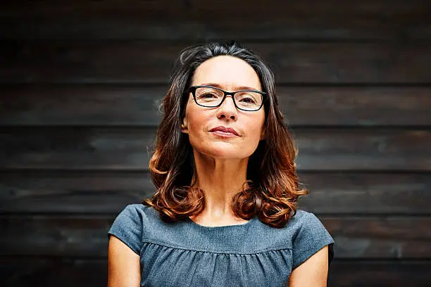 Portrait of mature businesswoman standing against a wooden wall in office