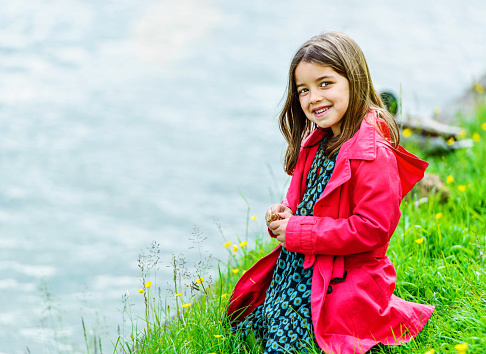 Natural portrait of cute child with greenery and water in the background