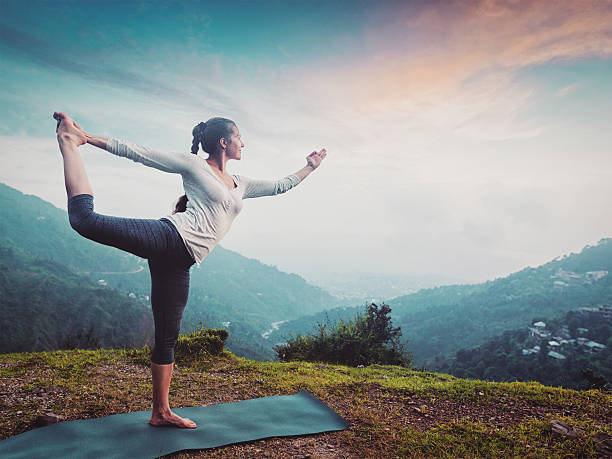 女性 ヨガをするスタンドの姿勢ナタラジサナ屋外の滝 - shiva posture ストックフォトと画像