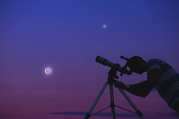istock Man looking at the night sky with telescope beside him. 627915248