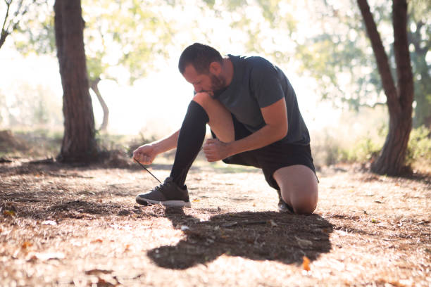 istock Young man tying his shoelaces in park 627918822