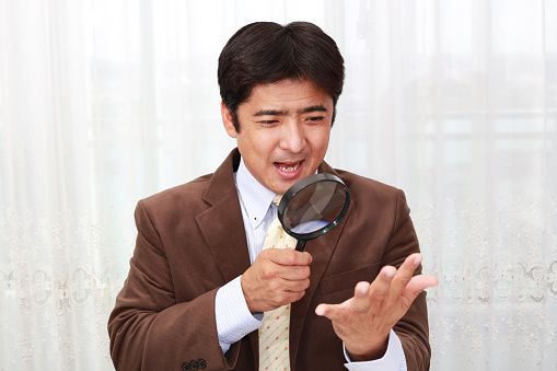 Smiling Asian businessman with a magnifying glass