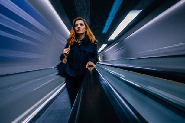 mujer de negocios de pie en la escalera mecánica - escalator people city blurred motion fotografías e imágenes de stock