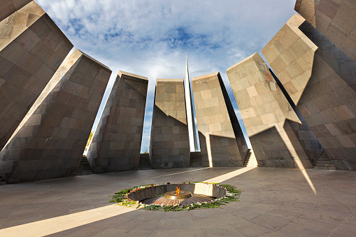 Yerevan, Armenia - September 22, 2016: Armenian genocide memorial monumentl and eternal flame surrounded with flowers left by visitors, in Yerevan, Armenia.