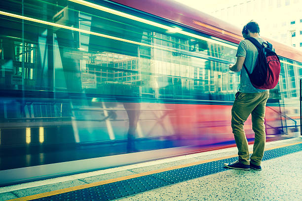 hombre joven con una mochila y auriculares esperando tren - subway station railroad station uk passenger fotografías e imágenes de stock