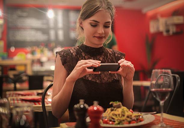 Picture of my meal Beautiful girl in black dress taking picture of her food in a restaurant noodles photos stock pictures, royalty-free photos & images