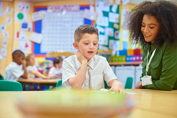 istock schoolboy reading to his teacher. 627928750