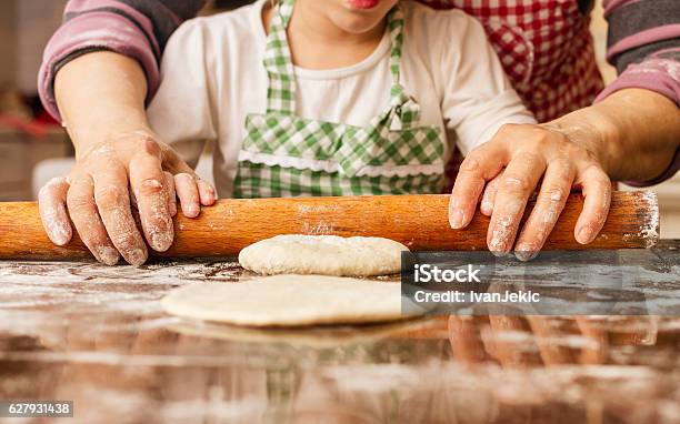 Grandma And Granddaughter Stretching Dough Stock Photo - Download Image Now - Grandmother, Cooking, Baking