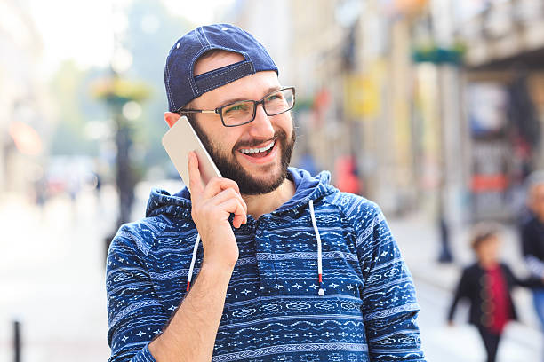istock Smiling man talking on smart phone on street 627931700