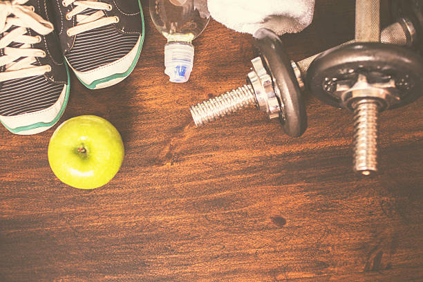 istock Fitness, exercise themed scene with barbells, sneakers, apple. 627933802