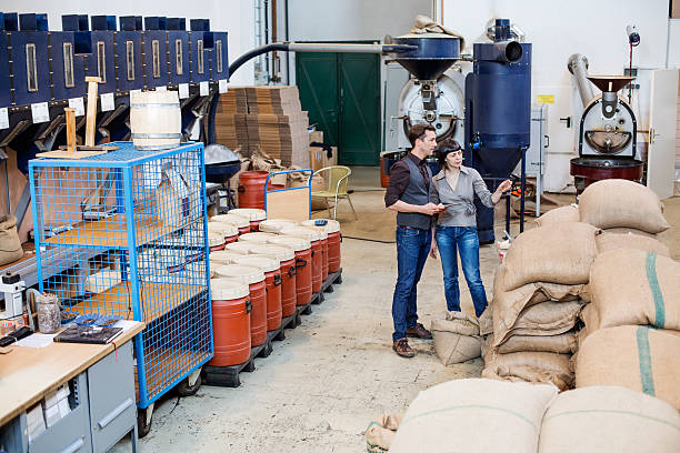 modern coffee roaster factory with two people working - sack burlap bag roasted imagens e fotografias de stock