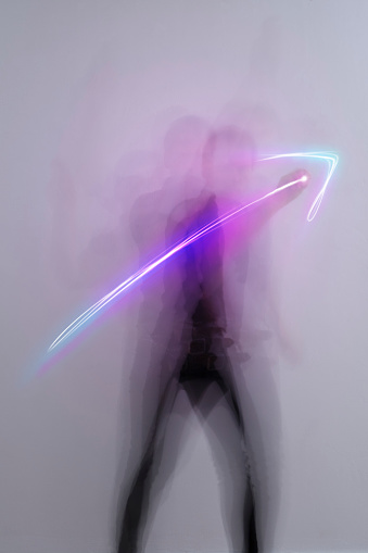 man in aktion drawing light trail symbols with laserpointer, time exposure