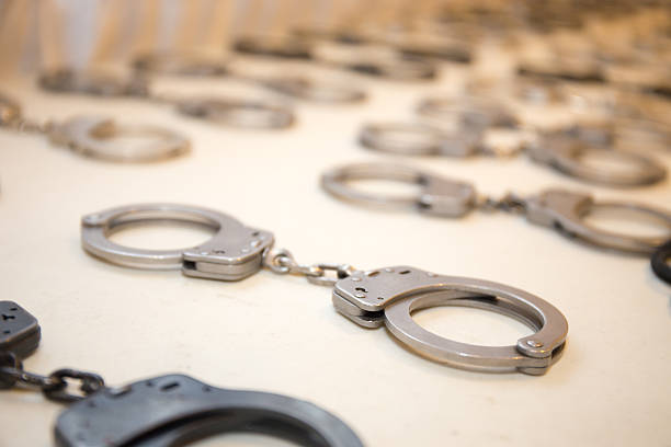 row of law enforcement silver metal  handcuffs on white table row of law enforcement silver metal  handcuffs prepare for training on white table wrongdoer stock pictures, royalty-free photos & images