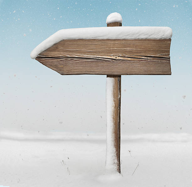 istock Wooden direction sign with less snow with snowfall on background 627967898