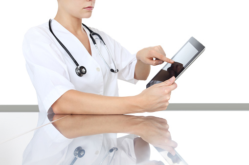 doctor at desk touch tablet in medical office, remot control device, concept