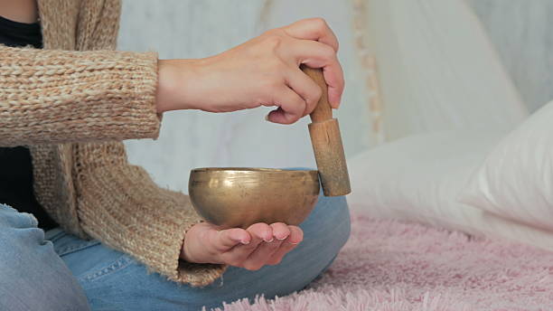 jeune femme en cardigan se relaxant avec le bol chantant du népal - tibetan culture music sound recovery photos et images de collection