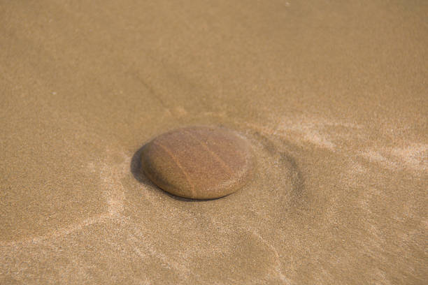 round pebble in the sand, in sea water