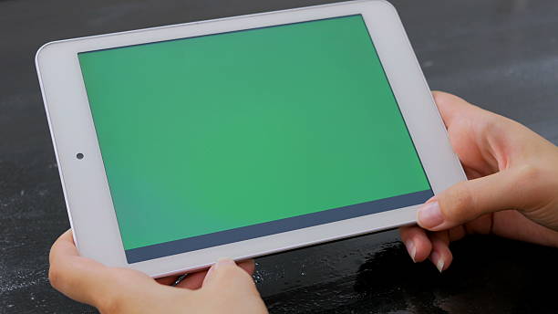 istock Woman looking at tablet computer with green screen 627976828