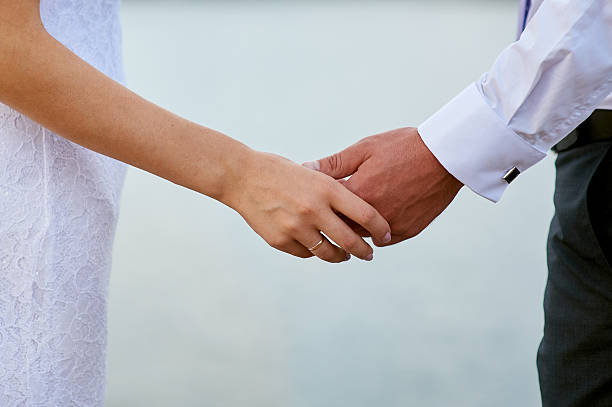 istock bride and groom holding hands in wedding day closeup 627984236