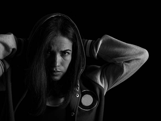 serious woman in hood looking at camera on black background with copyspace monochrome